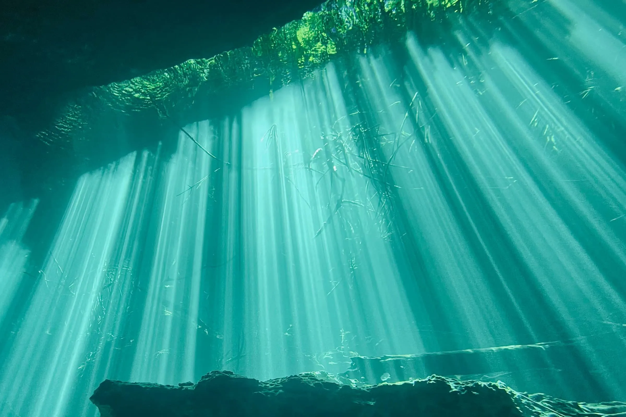 Beams of sunlight falling through clear teal water