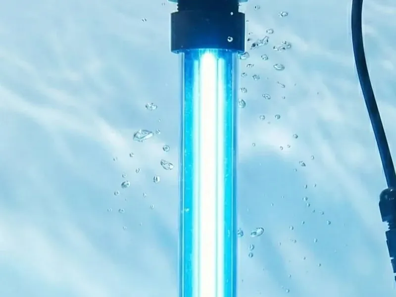A germicidal UV-C lamp glowing blue under clear water, bubbles rising around the tube